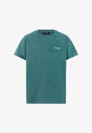 Junge mit türkisfarbenem Cap und T-Shirt, pinken Shorts und schwarzen Flip-Flops, stehend vor einem schlichten hellen Hintergrund.