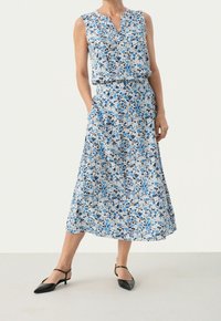 Květinové maxi šaty bez rukávů, modré a bílé vzory a výstřih do V. Mají stahovací pas a boční kapsy. Černé podpatky.