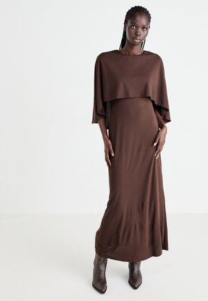 Brown maxi dress made of soft fabric, featuring a layered cape style at the top, with a fitted silhouette and long sleeves.