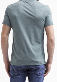 Green heather short-sleeve t-shirt with a round neckline; cotton blend fabric and smooth texture. Worn with blue jeans, showing back view.