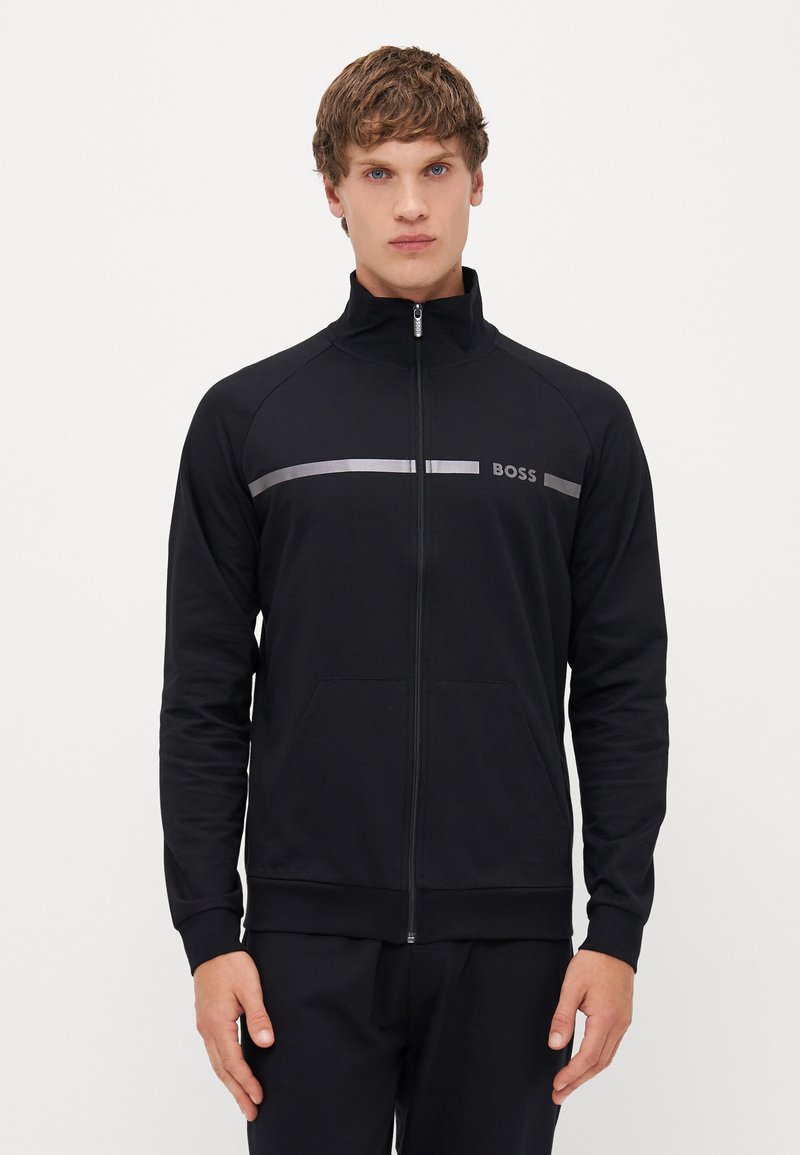 Zwarte zip-up trainingsjacket gemaakt van gladde stof. Heeft een hoge kraag, zijzakken en een zilveren streep met het "BOSS" logo over de borst.