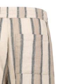 Beige and cream striped fabric pants with a visible back pocket, featuring a textured weave and contrasting dark stripes.