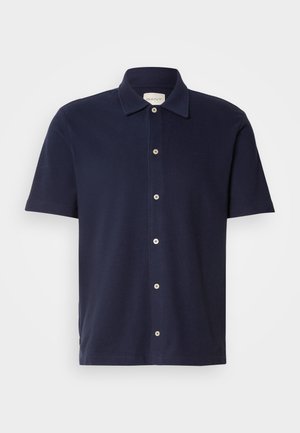 Mörkblå kortärmad polo med klassisk krage, med knappstängning och en liten, broderad logo på bröstet.