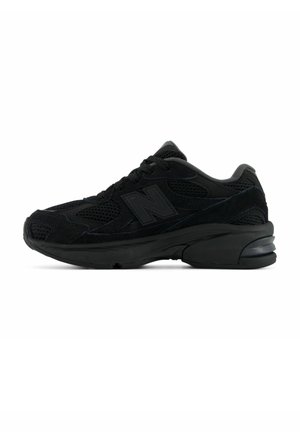 Schwarzer New Balance Sportschuh mit Mesh- und Wildleder-Obermaterial, dicker gepolsterter Sohle und Schnürverschluss, Seitenansicht auf weißem Hintergrund.