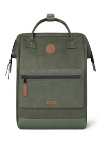 Sac à dos en simili cuir vert avec deux poignées, poche zippée à l'avant, accents texturés et un écusson rond. Forme rectangulaire compacte.