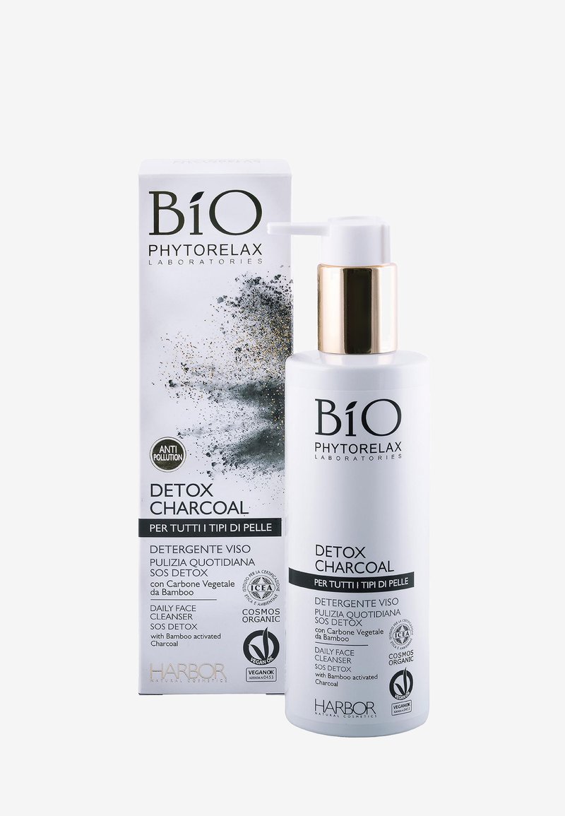 Biała butelka z dozownikiem pompkowym, ze złotym akcentem, opisana jako "Detoksykujący Węgiel". Towarzyszy jej prostokątne pudełko z czarno-białą grafiką.