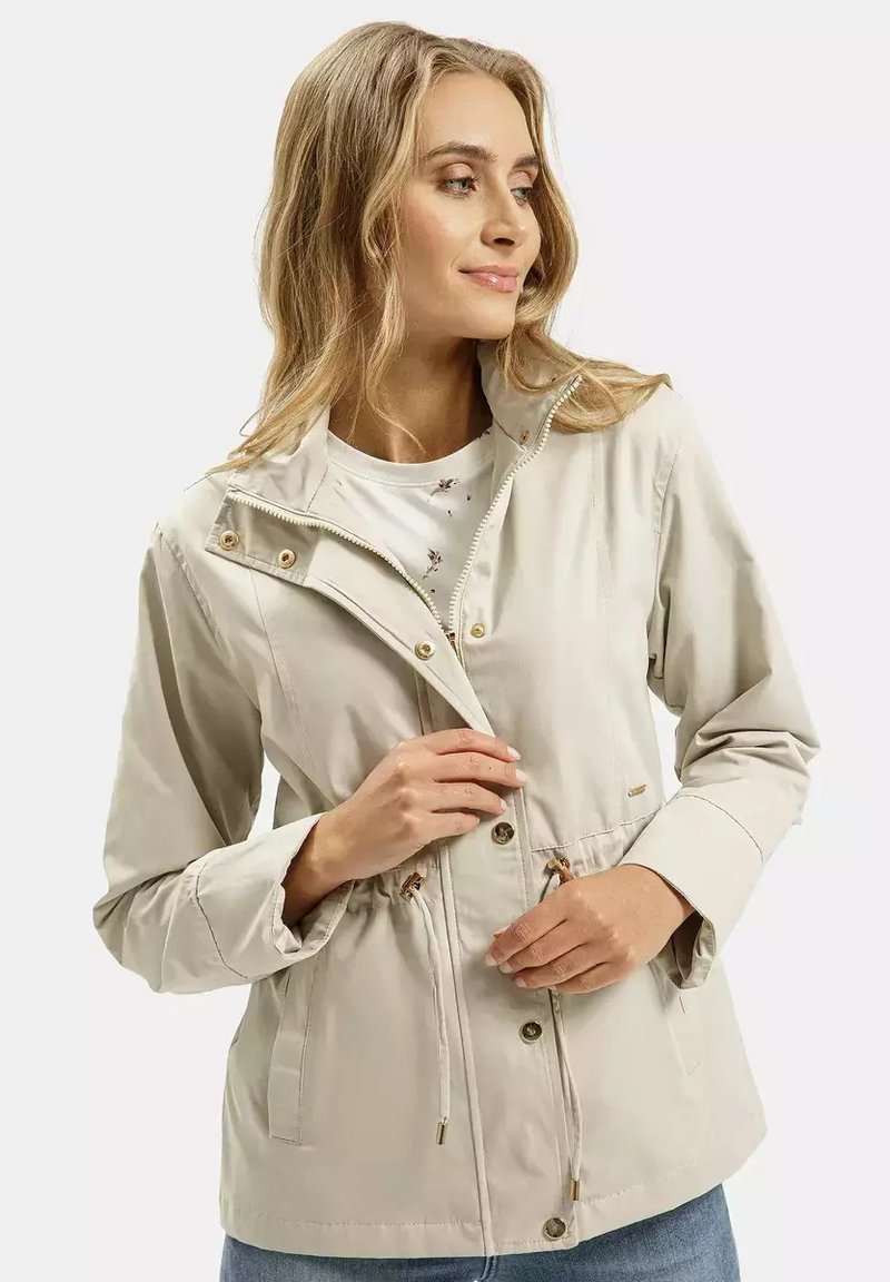 Jasno beżowa, lekką kurtka z paskiem na talii, z złotymi akcentami, zamkiem błyskawicznym z przodu oraz zatrzaskowym zapięciem, z kołnierzem podnoszonym.