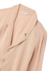 Blusa beige con colletto a punta, dettagli con bottoni e spalle plissettate, realizzata in tessuto liscio e caratterizzata da un design semplice e strutturato.