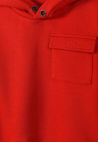 Felpa rossa con tessuto testurizzato, dotata di una tasca frontale e accessori neri a contrasto intorno al collo. Design semplice, colore uniforme.