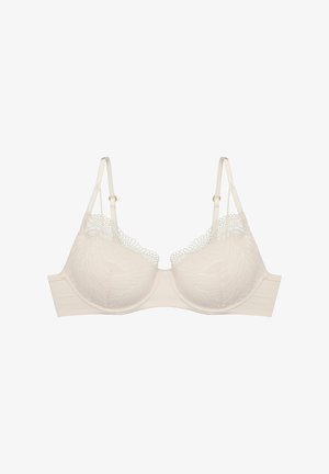 Hellbeige BH mit Spitze am oberen Rand, glatten Schalen, verstellbaren Trägern und einem stabilen Unterband. Das Gewebe zeigt ein florales Muster.