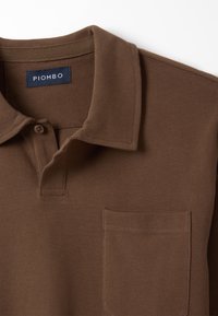 Braun Polohemd aus strukturiertem Material, mit einer geknöpften Knopfleiste, Kragen und einer Brusttasche mit subtilen Nähdetails.