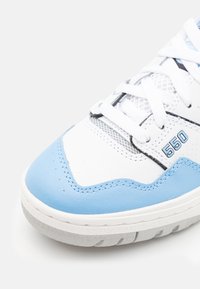 Białe sneakersy z jasnoniebieskimi akcentami. Wykonane z materiałów skórzanych i siatkowych, z okrągłym noskiem, białymi sznurowadłami oraz teksturowaną gumową podeszwą.
