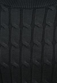 Pull en maille noire présentant un motif de chaîne en relief texturé, avec un col côtelé et une texture de tissu lisse partout.