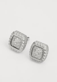 Orecchini a perno in argento di forma quadrata, con un design di leone al centro e un bordo testurizzato e rialzato con accenti simili a diamanti.