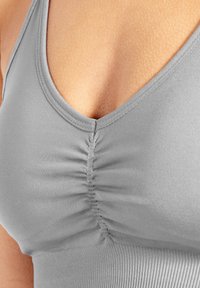 Débardeur gris avec un col en V profond, un subtil effet froncé au centre, et une texture de tissu lisse et extensible.