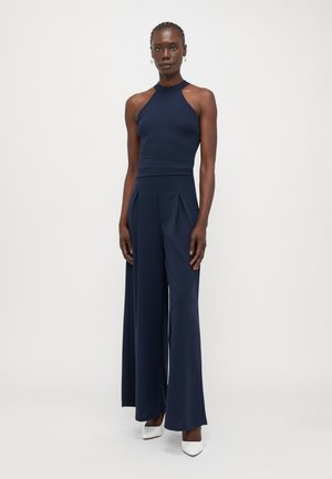 Navy blue jumpsuit with a fitted bodice and wide-leg trousers. Features a high neckline and pleats on the front, made from a smooth fabric.