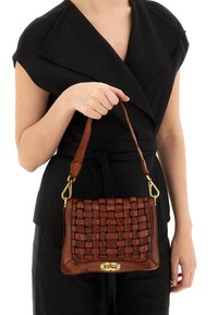 Borsa a tracolla in pelle intrecciata marrone con forma rettangolare, hardware dorato e tracolla corta, esposta su un abbigliamento nero.
