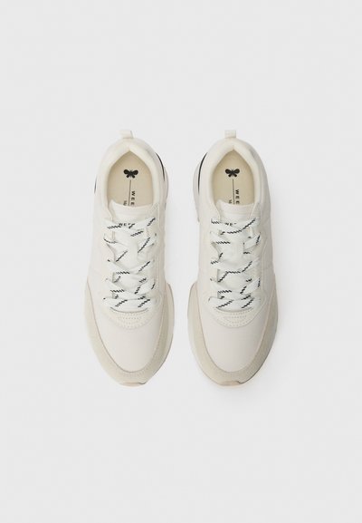 Pantofi sport albi au un superior neted cu accente din suede, șireturi texturate și o talpă căptușită. Detaliile negre adaugă contrast.