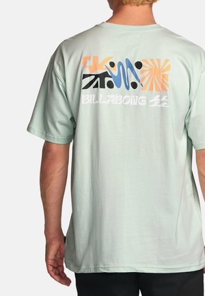 Camiseta de algodón verde menta con gráficos abstractos coloridos en la parte posterior, con texto "BILLABONG", mangas cortas y un ajuste relajado.