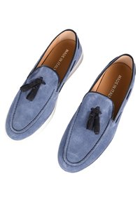 Mocassini in suede blu con dettagli in nappine nere, suola in gomma bianca e cuciture lungo il bordo. Fatto in Italia.