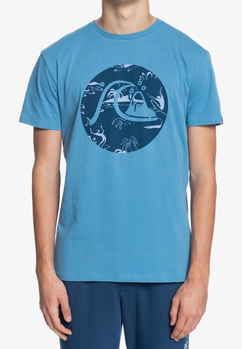 Blue cotton t-shirt with short sleeves and a round neckline. Features a circular navy graphic design with abstract patterns.
