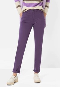 Pantaloni viola in cotone con design a gamba dritta. Risvolti sulle caviglie e tasche frontali. Tessuto leggero abbinato a scarpe slip-on color crema.
