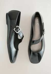 Fekete lakkbőr cipő Mary Jane kialakítással, ezüst csatos pánttal, lekerekített orrú és párnázott belsővel.