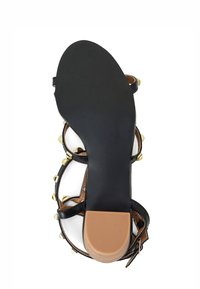 Zwarte sandaal met een platte zool, voorzien van gouden studaccenten, dunne banden en een gestructureerde voetbed. Rubberen loopzool voor grip.