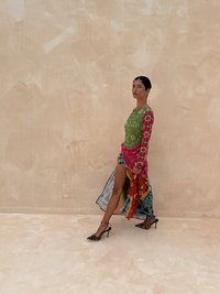 Farverig multitasket kjole med en grøn top og røde blomsterærmer, lagdelt med en blå og orange nederdel, kombineret med sorte leopardprint hæle.