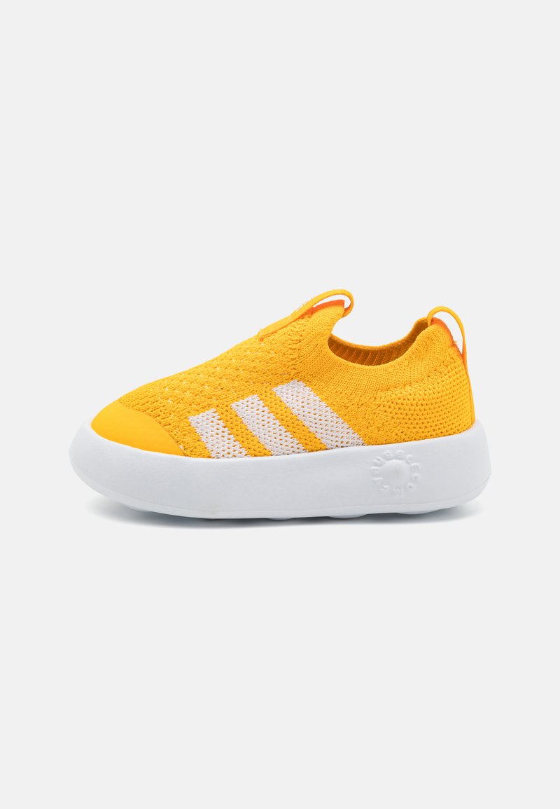Yellow knitted slip-on shoe with a white sole and three white stripes on the side. Features elasticized collar and pull tab for easy wear.