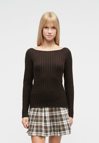 Ruda ilga rankovėmis, iškiloto audinio palaidinė su plačiu iškirpte, suderinta su languota raukšlėta sijonu, kuriame yra balta, ruda ir žalia spalvos.