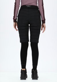 Black padded shorts with a textured finish, featuring a high waistband and a sleek design, paired with black leggings and sturdy black shoes.