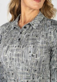 Koszula z guzikiem w czarno-białym abstrakcyjnym wzorze, z kołnierzykiem, gładką teksturą i krótkimi rękawami.