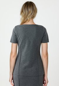 Graues Kurzarmoberteil mit quadratischem Ausschnitt, figurbetontem Design, weicher Textur und nahtloser Verarbeitung, kombiniert mit einem passenden Rock.