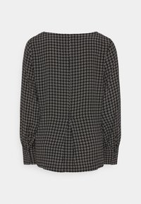 Schwarze Bluse mit langen Ärmeln, die ein weißes Gittermuster aufweist, runden Ausschnitt und Raffung im Rücken für eine taillierte Passform.