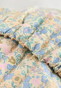 Floral-patterned fabric with pastel colors, featuring blue and pink flowers on a cream background. Textured with gathered stitching details.