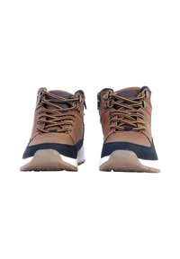 Zapatos de senderismo sintéticos marrones con acentos negros, superficie texturizada, cordones beige y suelas de goma blanca; diseño de media caña con collarín acolchado.