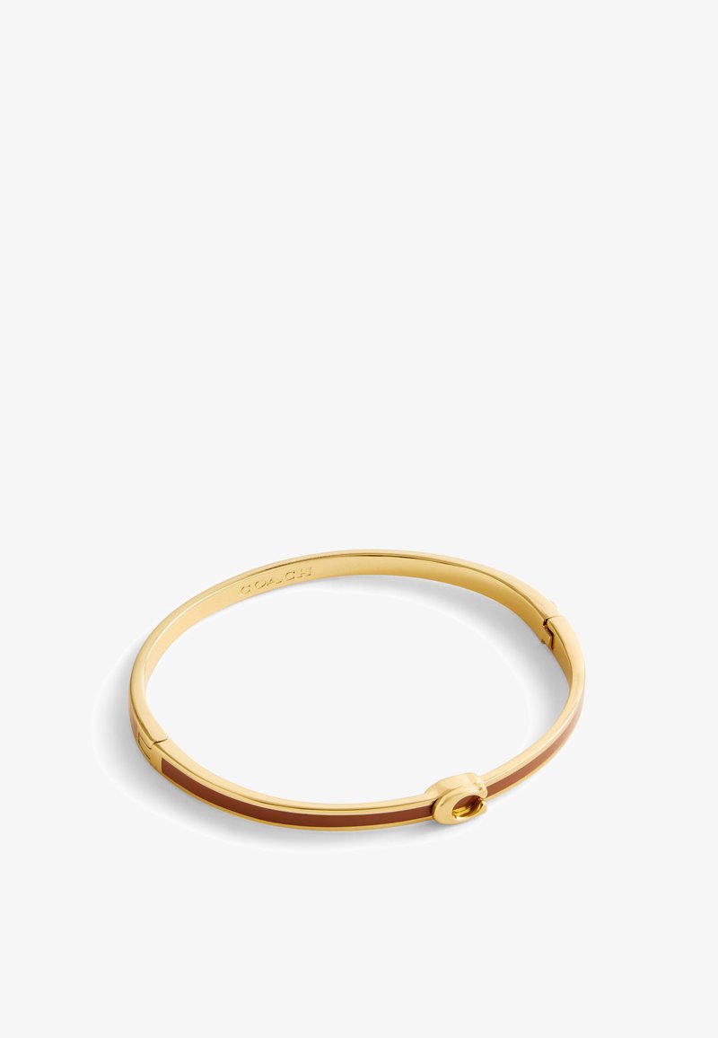 Jonc en métal doré fin avec une finition lisse et une fine bande d'accent marron. Présente un détail de fermoir circulaire pour la fermeture.