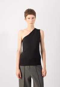 Top negro de un solo hombro hecho de tela suave; diseño ajustado. La modelo lo combinó con pantalones grises claros, con pliegues. Estilo simple y monocromático.