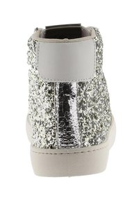 Sneaker argentato con paillettes e un tacco metallico lucido, accompagnato da una suola grigia morbida. La texture è scintillante con un pannello posteriore liscio.