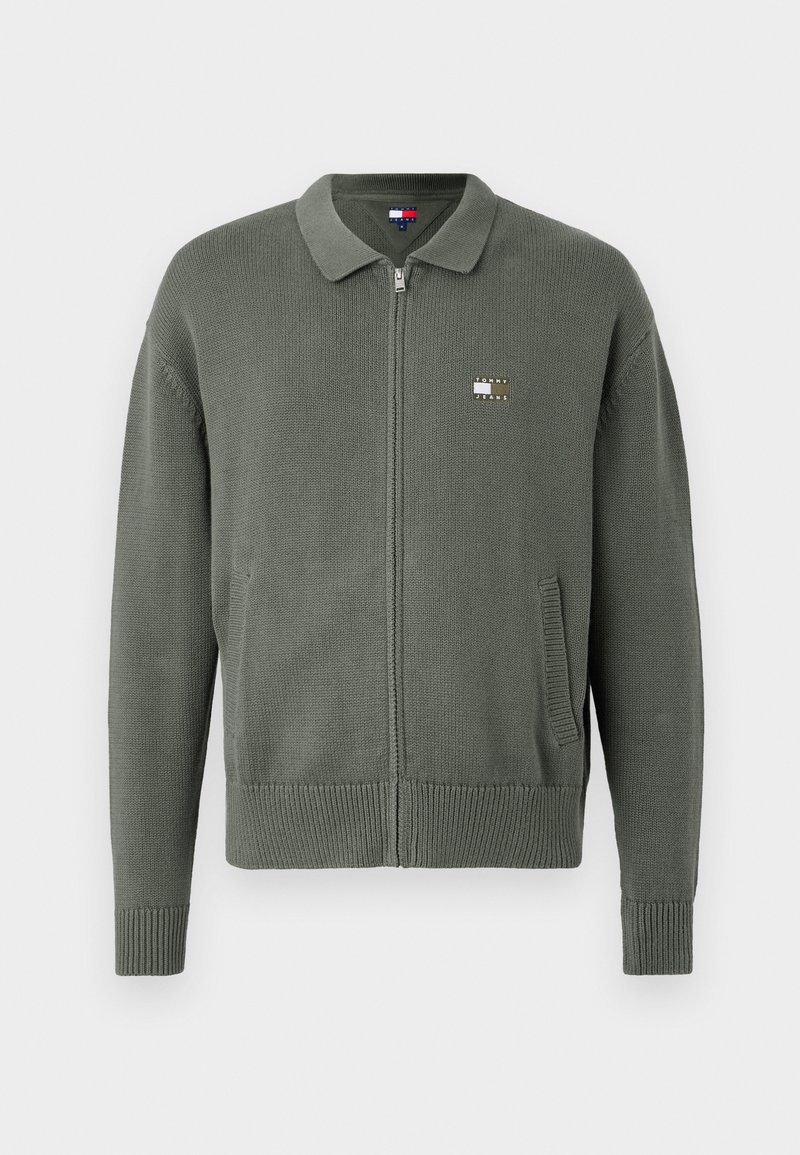 Green zip-up cardigan made of textured knit fabric featuring a collar, side pockets, and a small logo patch on the chest.