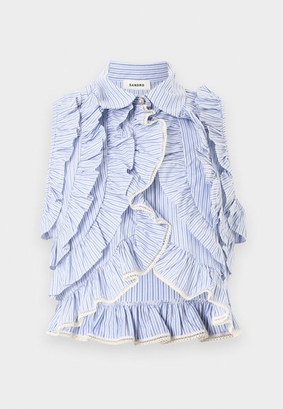 Μπλε και λευκή ριγέ αμάνικη μπλούζα με βολάν που κυλούν κατά μήκος του εμπρός μέρους και στις άκρες, με μυτερό γιακά και ετικέτα με το λογότυπο της μάρκας στο εσωτερικό.