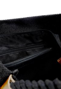 Sort tekstil taske indvendigt med en tekstureret kant, der har to lynlåslommer og en glat foring.