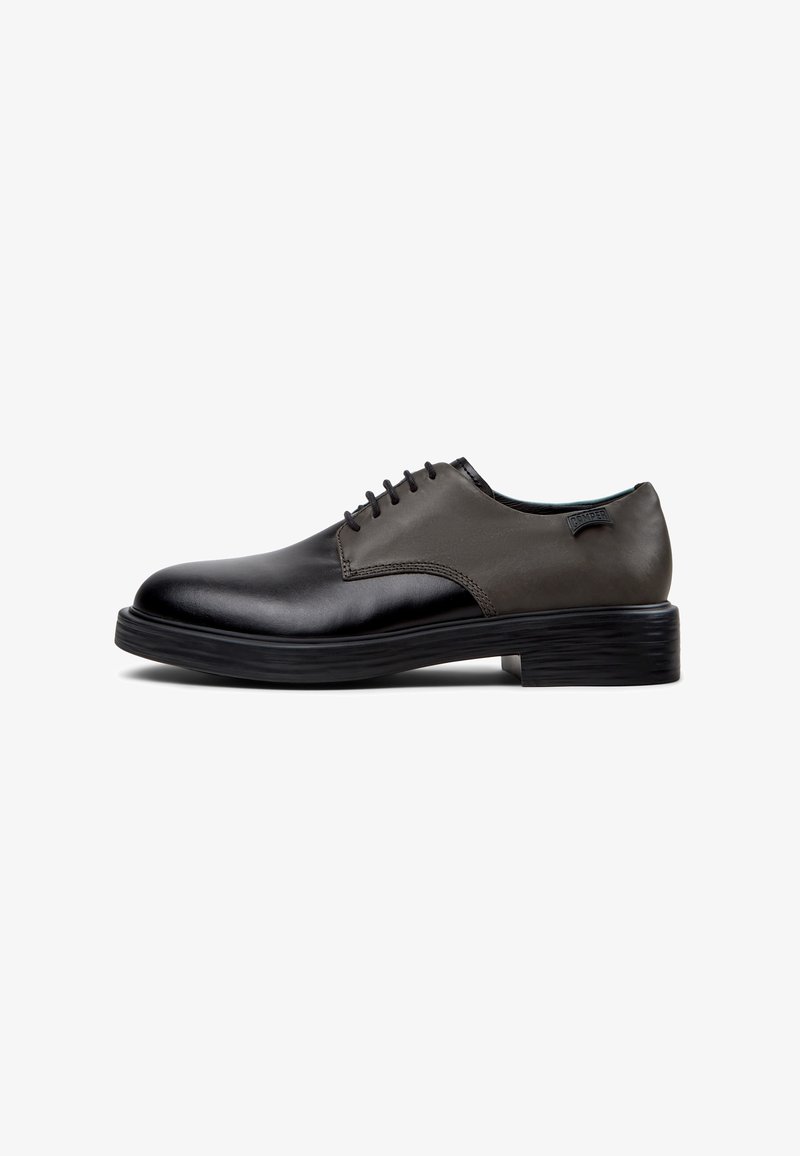 Chaussure habillée en cuir noir et gris foncé à lacets avec un petit talon empilé et un bout arrondi lisse, vue latérale sur fond blanc.