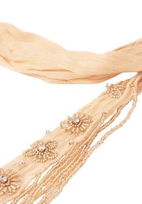 Bufanda beige hecha de tela transparente, adornada con patrones florales embellecidos y detalles de flecos con cuentas. Ligera y texturizada.