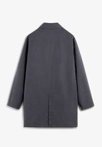 Abrigo largo de color gris oscuro con un diseño simple, cuello puntiagudo y una abertura trasera para mayor libertad de movimiento. Textura suave y estilo minimalista.