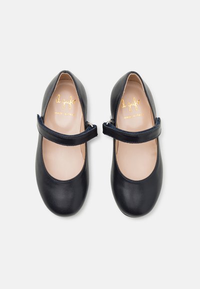 Chaussures Mary Jane en cuir noir avec un bout rond, une sangle à la cheville et une texture lisse. L'intérieur présente un branding en relief doré.