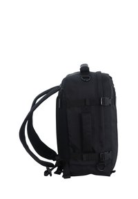 Mochila negra con forma rectangular, material de tela, correas ajustables, múltiples hebillas y un panel de malla en un lado para ventilación.