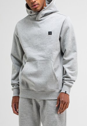 Grauer Kapuzenpullover aus weichem Stoff. Verfügt über eine Kängurutasche, gerippte Bündchen und ein kleines schwarzes Logo-Patch auf der Brust.