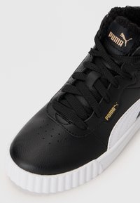 Crni Puma visoki teniski u dodatak s bijelim potplatom, crnim vezicama, zlatnim Puma logotipima i jastučićem oko gležnja na bijeloj pozadini.